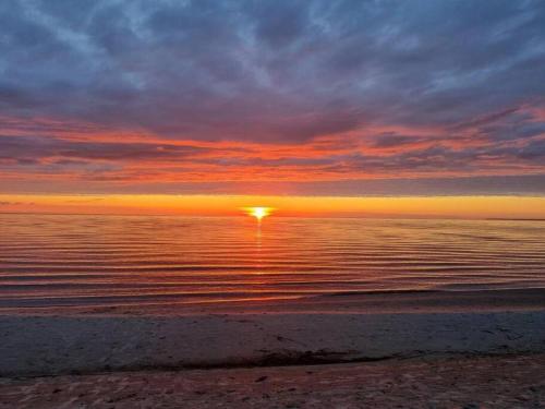 a sunset over the ocean with the sun in the sky at Seashell Albatross Boutique Apartment in Ķesterciems