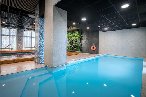 een zwembad met blauw water in een gebouw bij Seashell Albatross Boutique Apartment in Ķesterciems