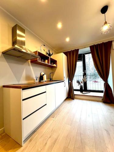 a kitchen with white cabinets and a wooden floor at Seashell Albatross Boutique Apartment in Ķesterciems
