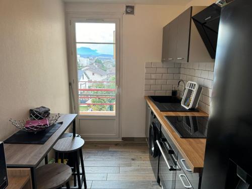 une cuisine avec vue sur la ville depuis une fenêtre dans l'établissement Appartement proche Grenoble centre et campus, à Saint-Martin-dʼHères