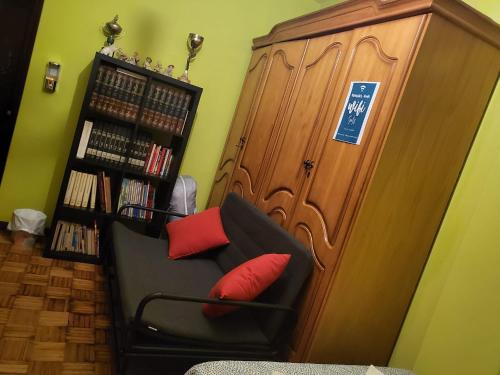 una silla negra con almohadas rojas sentada junto a un estante de libros en EL BUDHA, en Pobra do Caramiñal