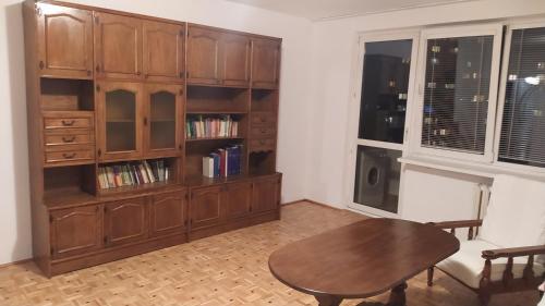 Uroczy apartament z bezpłatnych parkingiem في وارسو: غرفة معيشة مع طاولة ورف كتاب