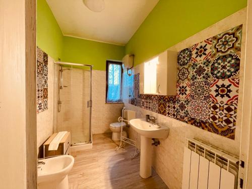y baño con paredes verdes, lavabo y ducha. en Maremma Nel Tufo, en Pitigliano