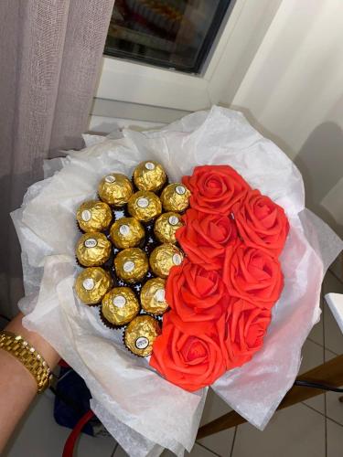 une personne détenant un bouquet de roses et de chocolats en forme de cœur dans l'établissement Suite romantique avec jaccuzy à la gare de Montpellier, à Montpellier