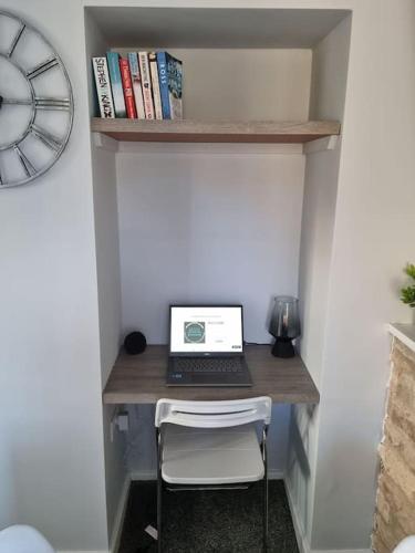a desk with a laptop computer on a wall with a clock at Flamingos Nest Oxford Countryside Apartment Oxford - Bicester Village - Blenheim Palace - WiFi- Free Parking in Oxford