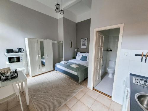a bedroom with a bed and a bathroom with a sink at Mikszáth Apartments Budapest in Budapest