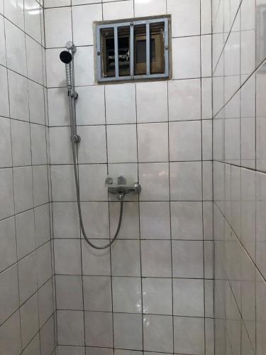 a shower in a white tiled bathroom with a window at Room in Guest room - Logerthine Cambridge Suriname in Paramaribo