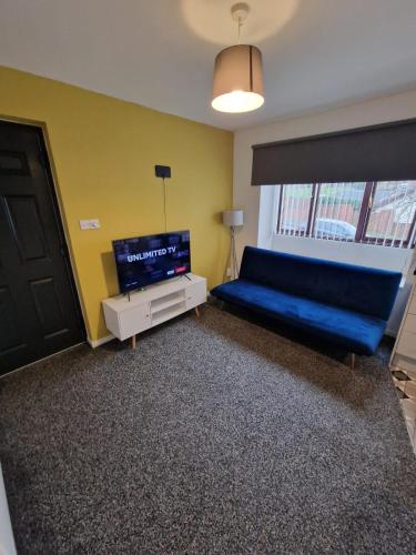 a living room with a blue couch and a tv at 1 bedroom Windy Nook -Great monthly offers in Sheriff Hill