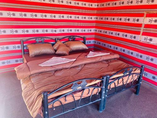 a bed in a room with a red wall at Wolf Trail Adventure in Wadi Rum