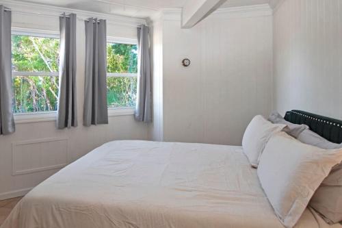 a bedroom with a large white bed with two windows at OceanBliss: Exuma, Waterfront sleeps 8 in Michelson