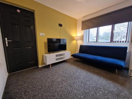 uma sala de estar com um sofá azul e uma televisão em 1 bedroom Windy Nook -Great monthly offers em Sheriff Hill