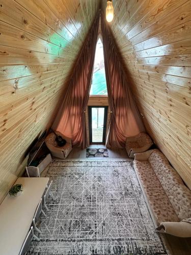 an attic room with a large window in a wooden house at Dolinka Lodge in Dzhergalan