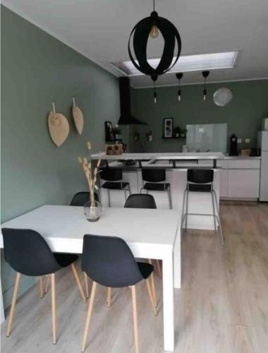 une salle à manger avec une table et des chaises blanches dans l'établissement Maison récente 2 chambres jardin et parking, à Wasquehal