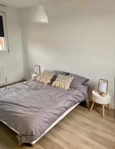 une chambre avec un grand lit avec deux tables de nuit dans l'établissement Maison récente 2 chambres jardin et parking, à Wasquehal