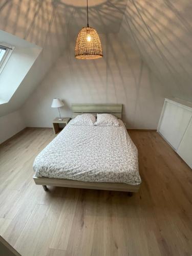 a bedroom with a bed in a attic with a lamp at Petite maison 2 chambres in Tréauville