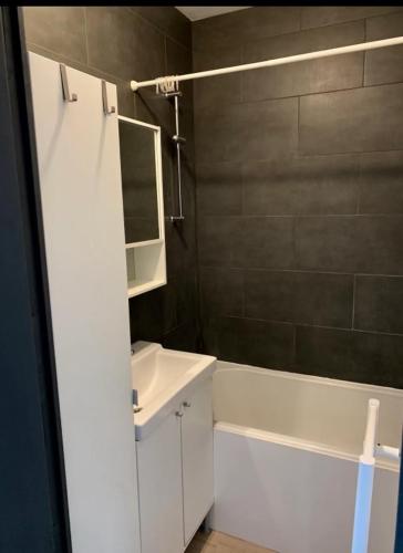 une salle de bain avec un lavabo, une baignoire et un miroir dans l'établissement Maison récente 2 chambres jardin et parking, à Wasquehal