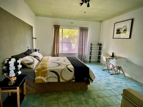 a bedroom with a bed and a table and a window at Horizon Green Guest House in Randfontein