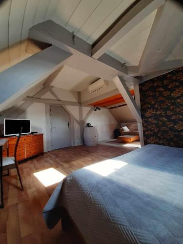 - une chambre mansardée avec un lit, un bureau et une télévision dans l'établissement Le Domaine des Papillons, à Beaujeu-Saint-Vallier-Pierrejux-et-Quitteur