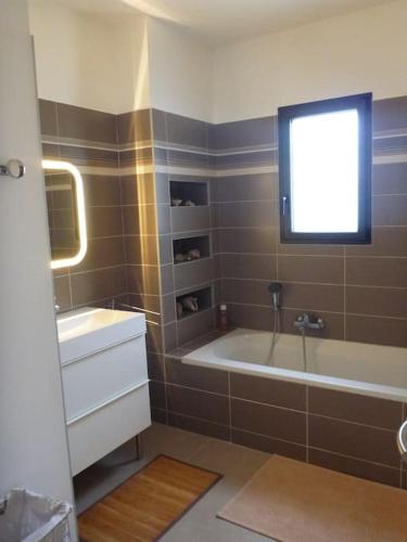 une salle de bain avec une baignoire, un lavabo et une fenêtre dans l'établissement 3 bedrooms new house with heated swimming pool, à Carpentras