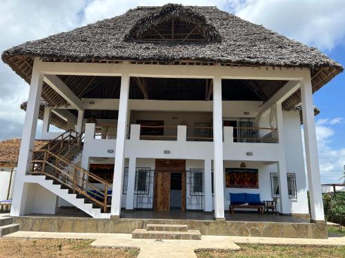 una grande casa bianca con tetto di paglia di Nyumbani Tamu a Watamu