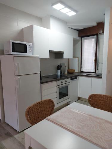 a kitchen with white cabinets and a white refrigerator at Primera línea de playa centro in Noja