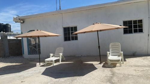 two chairs and two umbrellas in front of a building at Cocklestop Inn, Jamaica in Pond Side