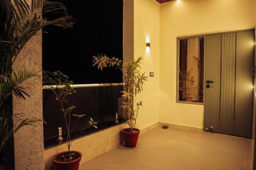 a hallway with two potted plants next to a window at Anirudh Homestay in Agra