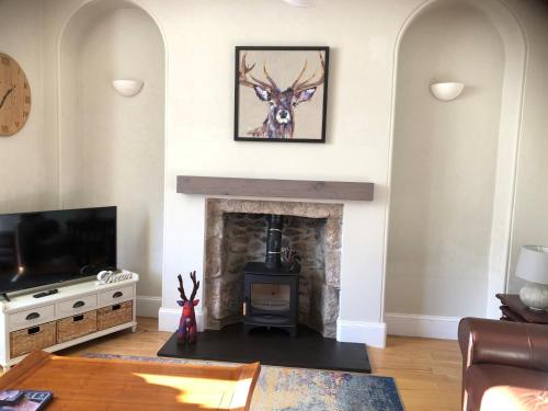 a living room with a fireplace and a picture of a deer at Spacious 2 Bedroom Flat in heart of Ballater in Ballater