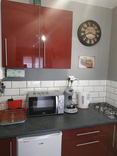 a kitchen with a microwave and a clock on the wall at studio avec terrasse "Le Loup" in Lamotte-Beuvron
