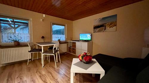 Una sala de estar con una mesa y sillas y un televisor. en Bungalow zur Kühlung, en Kühlungsborn