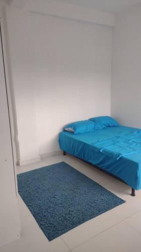 a bedroom with a blue bed and a blue rug at Apartamento bem localizado in Joinville