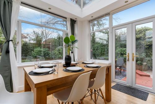 a dining room with a table and chairs and large windows at Birmingham Gem-Stylish 5 Bed house near NEC, BHX, HS2 - Huge Parking & Fast WiFi! in Kingshurst