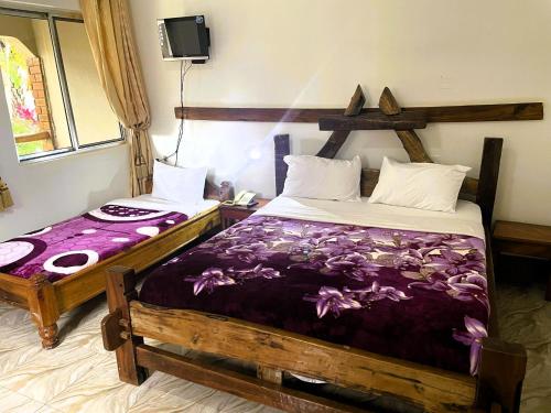 a bedroom with two beds with purple sheets at Home Feeling Neneu Lodge in Moshi