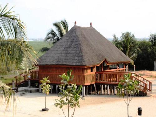 a large wooden building with a thatched roof at ASSOUKA Eco-Village du lac Nokoué in Abomey-Calavi