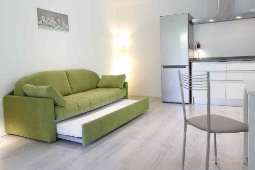 a living room with a green couch and a kitchen at Residence Gonda&Giuliano in Borso del Grappa