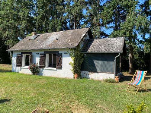ein kleines weißes Haus mit einem Stuhl im Hof in der Unterkunft Cottage du Diot, son lac et son île in Bannegon