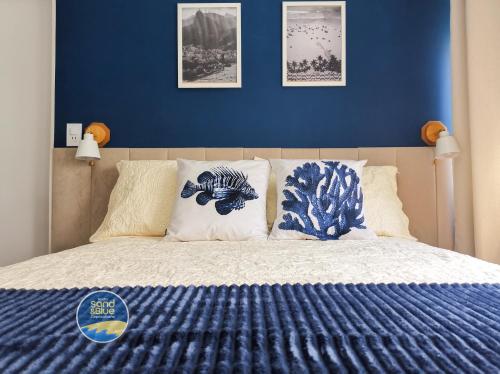 a bedroom with a blue wall and a bed with pillows at Studio Sand & Blue Copacabana Beach in Rio de Janeiro