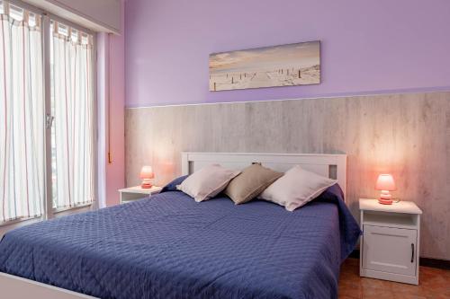 ein Schlafzimmer mit einem blauen Bett mit zwei Tischen und zwei Lampen in der Unterkunft H11 [House of Colors] Parcheggio in Taggia