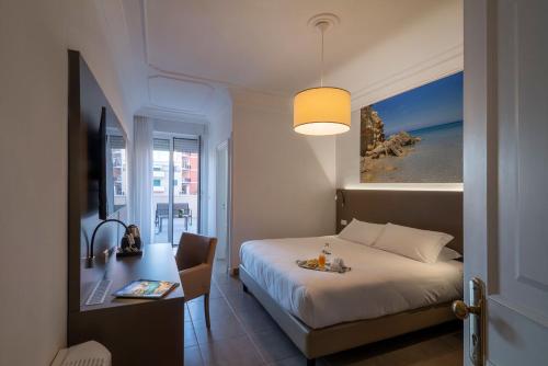 una camera d'albergo con letto, scrivania e tavolo di Hotel Delle Palme a Lecce
