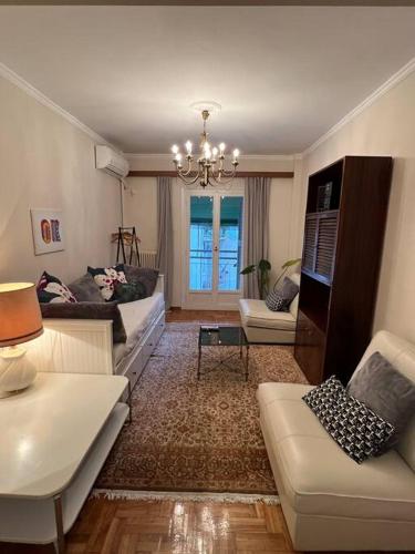 Una sala de estar con sofás y una lámpara de araña. en 4th floor cosy apartment in Metaxourgeio, en Atenas