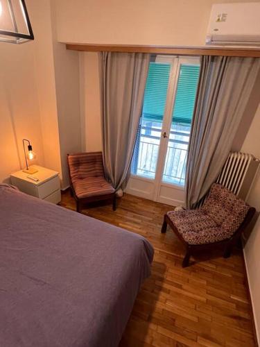 Un dormitorio con una cama y una silla y una ventana. en 4th floor cosy apartment in Metaxourgeio, en Atenas