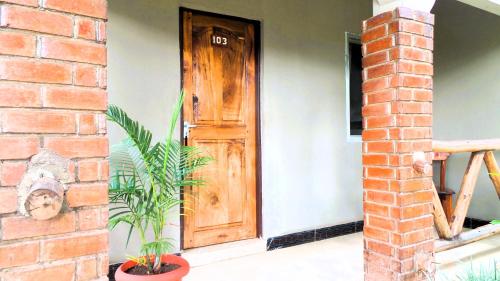 a house with a wooden door and a brick wall at Home Feeling Neneu Lodge in Moshi