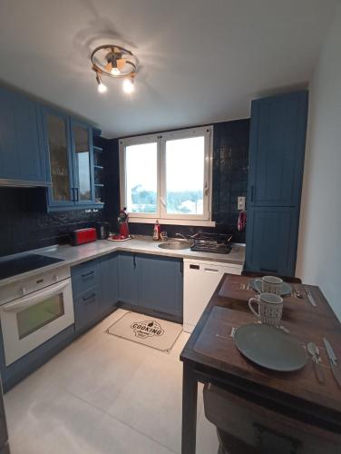 een keuken met blauwe kasten en een houten tafel bij Chambre privée 1 dans un appartement - Pessac in Pessac