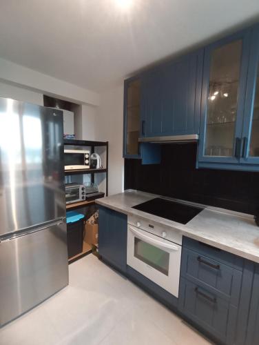 een keuken met blauwe kasten en een roestvrijstalen koelkast bij Chambre privée 1 dans un appartement - Pessac in Pessac