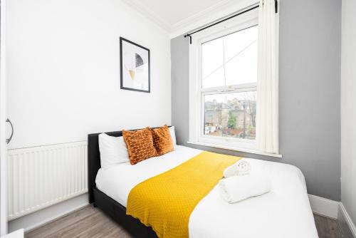 um quarto com uma cama e uma janela em Spacious 3 BR Near Walthamstow Station - 10 Min Walk em Londres