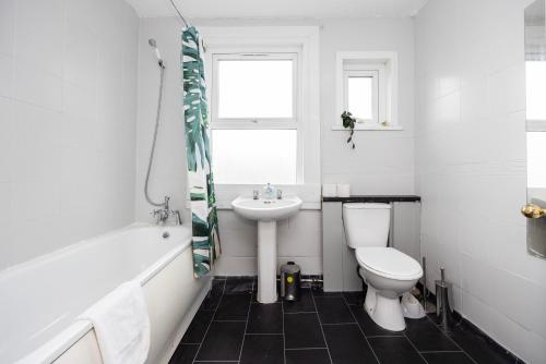 a white bathroom with a sink and a toilet at Spacious 3 BR Near Walthamstow Station - 10 Min Walk in London