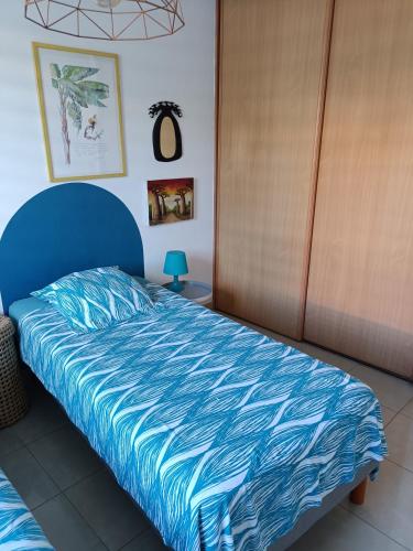 a bed with a blue comforter in a bedroom at appartement les pieds dans l'eau dans résidence de standing in Le Diamant