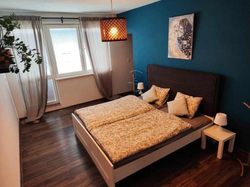 a bedroom with a bed and a blue wall at Apartmán Dominika in Rovinka