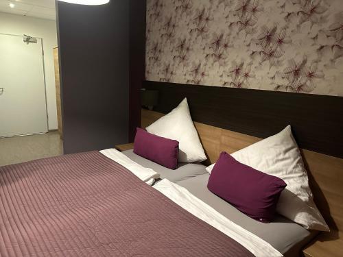 a bedroom with a bed with purple and white pillows at Hotel Efcannos Dornberg Carree in Vechelde