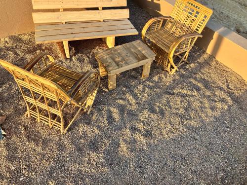 three chairs and a wooden bench next to a building at בריזה במדבר in Idan
